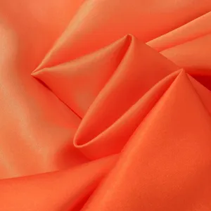 Nahaufnahme von hellorangem Satinstoff mit glatter Textur und elegantem Glanz für Bekleidung.