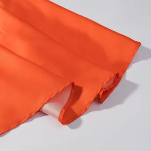 Heller orange Kleid Saum Detail, glatter Satin Textur Stoff Nahaufnahme mit sauberen Nähten.