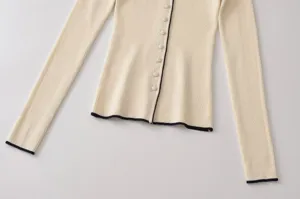 Cardigan de punto acanalado beige de manga larga con ribete negro contrastante y botones.