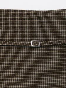 Primo piano dettagliato della vita di gonna pantalone a quadri marroni con fibbia argentata.