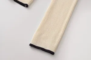 Primer plano de la manga del suéter de punto con ribete de contraste negro y textura acanalada.
