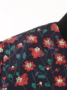 Close up detail of women jacket fabric featuring vibrant red floral print and black rib collar.