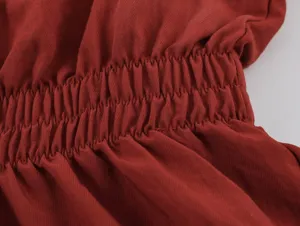 Detailed shot of dark red women clothing elastic smocked waist design, premium textured fabric.