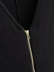Close-up view of black ribbed knit jumpsuit featuring a gold front half zipper and V-neck.