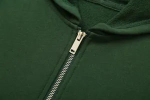 Close-up detail of green zip-up hoodie featuring metallic zipper and clean stitching.