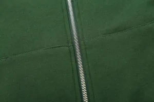 Close-up detail of dark green zip hoodie fabric and metallic zipper craftsmanship quality.
