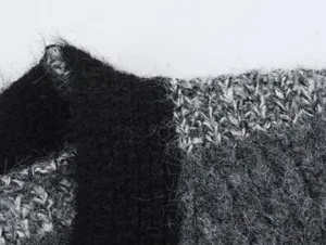 Gros plan du tissu de cardigan en tricot pelucheux montrant une texture douce en noir et gris.