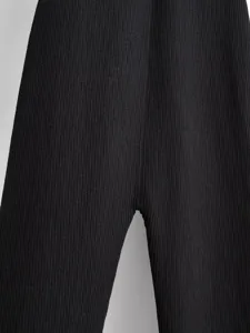 Close up detail of black ribbed knit pants showing texture and fabric quality craftsmanship.