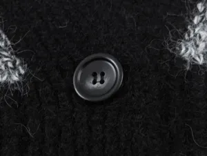 Gros plan sur le bouton du cardigan en tricot noir, texture duveteuse douce, accessoire chic.