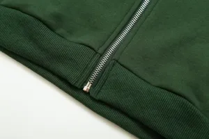 Dark green zip hoodie detail showing sturdy metal zipper and ribbed hem texture close-up.