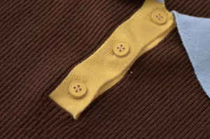 Close-up detail of women's ribbed knit top showing contrast yellow placket and button trim.
