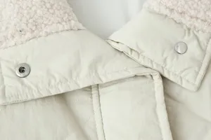 Dettaglio gilet trapuntato da donna con collo a risvolto in pile e chiusura a pressione.