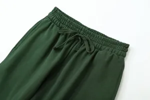 Close-up detail of dark green casual sweatpants elastic drawstring waistband fabric texture.