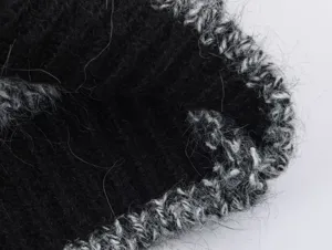 Gros plan sur la texture du tissu du cardigan en tricot noir et blanc, doux et confortable.