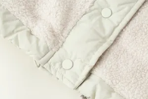 Gilet da donna in pile sherpa dettaglio ravvicinato con tessuto liscio e bottoni a pressione.