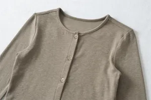 Detail view of a women's crewneck knit cardigan featuring front button closure with fine texture.