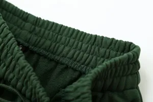 Close-up detail of dark green sweatpants elastic waistband with comfortable drawstring.