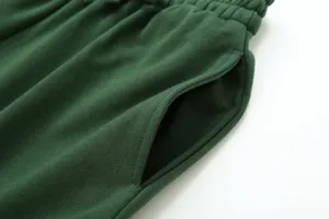 Close-up detail of dark green casual sweatpants pocket, showing soft cotton fabric texture.