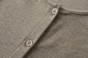 Close-up detail of knitted cardigan fabric, fine texture, round neckline, and button placket.
