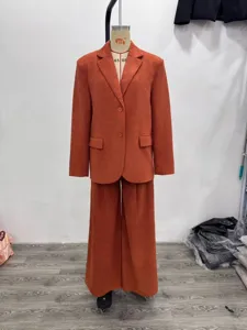 Corduroy suit detail shot, lapel blazer and wide-leg trousers in warm rust orange.