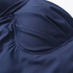 Dettaglio abito slim blu scuro elegante da donna con pieghe raffinate e cuciture fini.