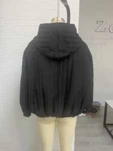 Detail view of women's black hooded puffer jacket, showing vertical quilted texture and back design.