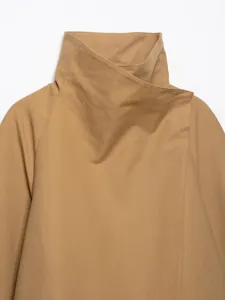 Detailaufnahme eines beigen Trenchcoats mit hohem Kragen und hochwertiger Stoffstruktur.