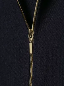 Detail view of the sleek gold metal zipper on the elegant dark blue knit cardigan.