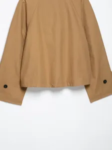 Detailansicht einer kurzen Khaki-Jacke,weite Ärmel mit dunklen Knöpfen,neutrale Hintergrund.