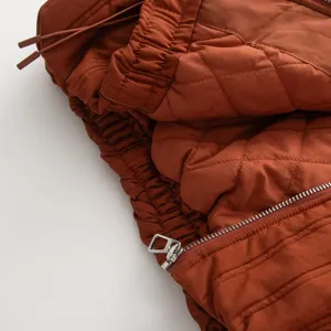 Close-up of quilted padded jacket detail featuring zipper closure and stand-up collar.