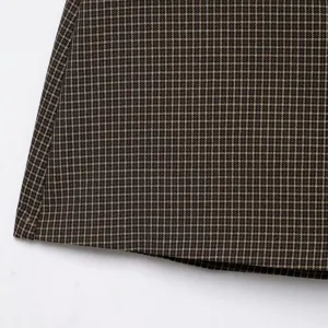 Dettaglio tessuto gonna a quadri pied de poule marrone, moda donna elegante.