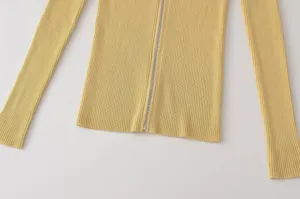 Primer plano detallado de un cárdigan de punto acanalado amarillo suave con cremallera fina.