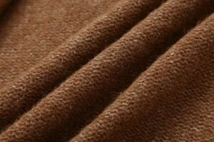 Gros plan detaille du tissu doux de cardigan marron montrant texture et melange de laine.