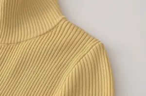 Vista detallada de la tela y el hombro del jersey de cuello alto de canalé amarillo.