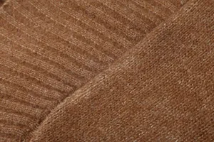 Gros plan sur le tissu du cardigan en maille côtelée marron avec une texture douce.