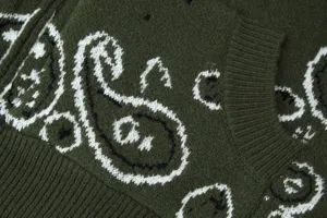 Detailed shot of dark green knitted cardigan sweater featuring classic white paisley patterns.