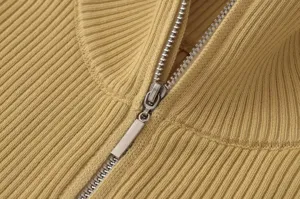 Vista detallada del jersey de punto acanalado amarillo con cremallera metálica y textura fina.
