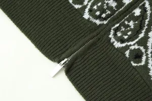 Close-up detail of green knitted cardigan showing retro jacquard pattern and metal zipper.