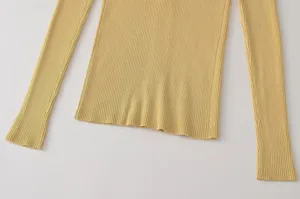 Detalle de top de manga larga de punto acanalado amarillo, primer plano tela.