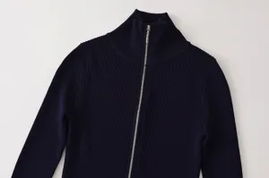 Detalle de cárdigan de punto acanalado azul oscuro con cremallera, cuello alto y elástico.