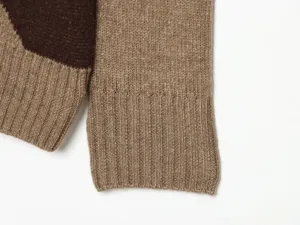 Primo piano del polsino del maglione da donna in maglia con motivo a rombi e costine.