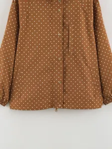 Brown polka dot hooded windbreaker jacket with snap buttons and pockets, stylish detail view.