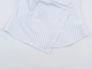 Close-up detail of women's blue and white striped asymmetrical wrap blouse hem and button.