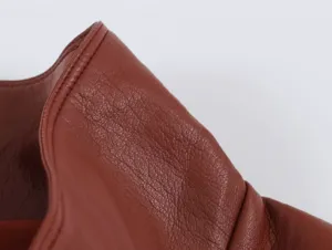 Primo piano dei dettagli del gilet in pelle marrone, texture di qualità e cuciture pulite.