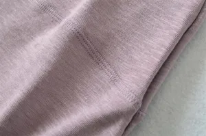 Close-up detail of knitted fabric texture with fine stitching, soft and delicate material quality.