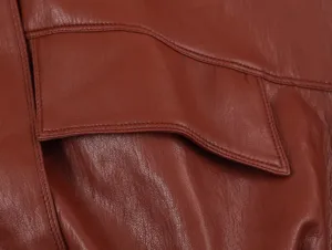 Dettaglio gilet in pelle marrone che mostra la patta della tasca e cuciture squisite.