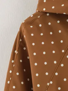 Brown polka dot trench coat fabric detail view, elegant women outerwear close up shot.