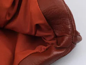 Primo piano dettaglio gilet pelle marrone mostra texture e qualità cuciture donna.