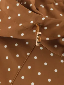 Brown polka dot hooded windbreaker coat detail, stylish commuter casual outerwear.