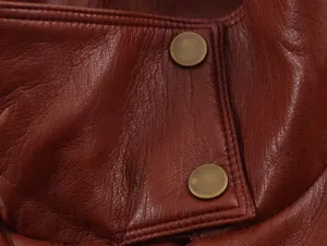 Dettaglio in primo piano di gilet in pelle rosso scuro, cuciture e bottoni metallici.